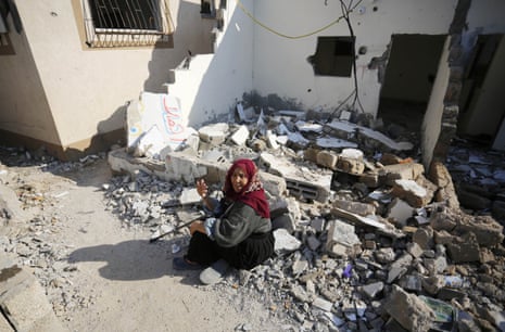 A woman sits in debris of a destroyed building after Israeli attacks in Deir al-Balah.