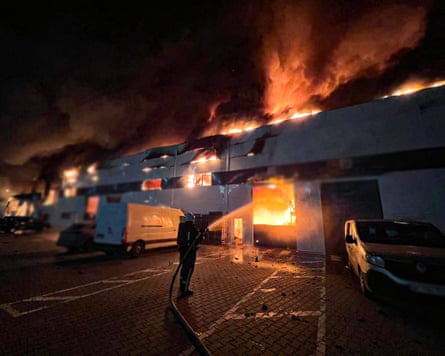 Firefighter spraying water on building in flames