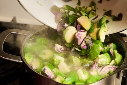 Brussels sprouts being dropped into a pot for par-boiling.