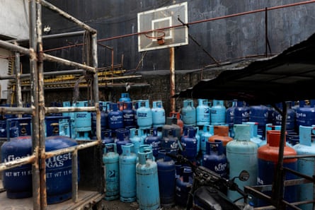 Dark blue, light blue and red LPG tanks are stacked in rows at a store.