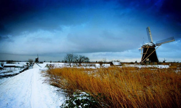 Overnight snowfall gives a fresh look to a Dutch scene of windmills on a flat landscape in Kinderdijk.