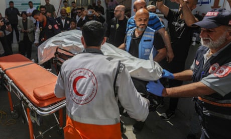 Red Crescent and other paramedics with body in white shroud on trolley