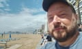 Mark Saxby looking at the camera with the beach and sea behind him