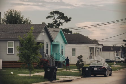a child standing outside a row of homes on a street with a parked car