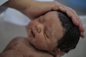 A hyper-realistic doll very closely resembling a human infant being washed