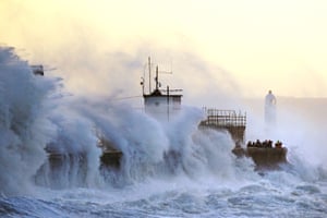 Bridgend, Wales: waves crash against the sea wall and Porthcawl lighthouse