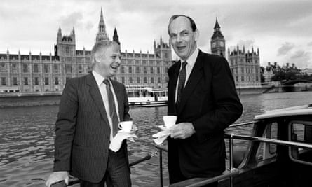 Chris Patten and Lord Crickhowell laughing as they drink tea on a boat on the Thames in front of the Houses of Parliament