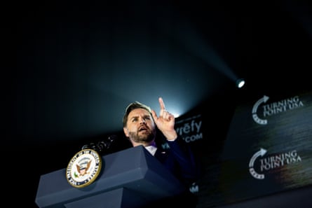 person wearing suit points while speaking at podium person wearing suit points while speaking at podium