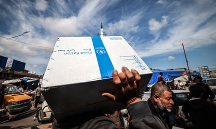 A person carries a box of food rations provided by the World Food Programme in Rafah.