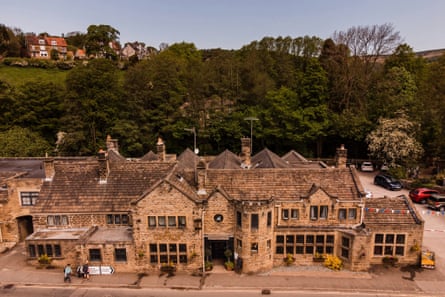 Very large old pub called the George at Hathersage with woodland behind it