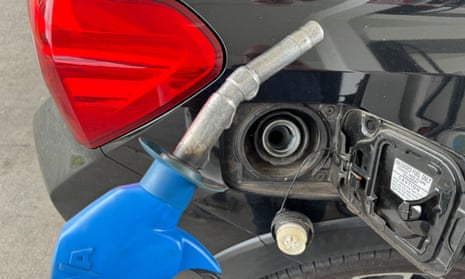 A petrol nozzle leaning against a car