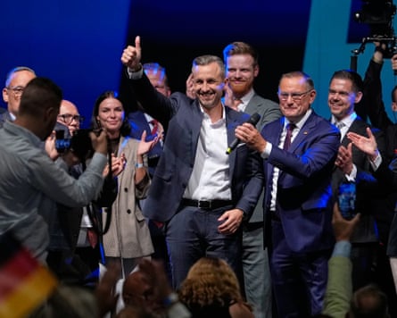 Ulrich Siegmund gives a thumbs up to the cameras while on stage surrounded by party members and supporters