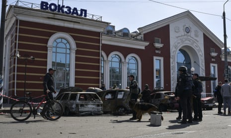 Ukrainian service personnel stand next to damaged cars outside Kramatorsk railway station