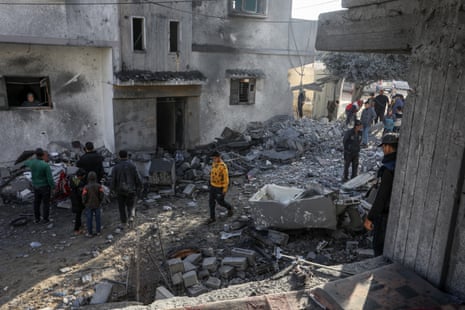 People walk through a street strewn with the debris of Palestinian houses in Rafah destroyed by Israeli strikes.
