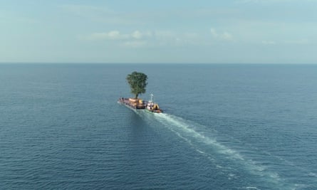 A tug pushes a single tree on a raft across a wide expense of sea towards the horizon