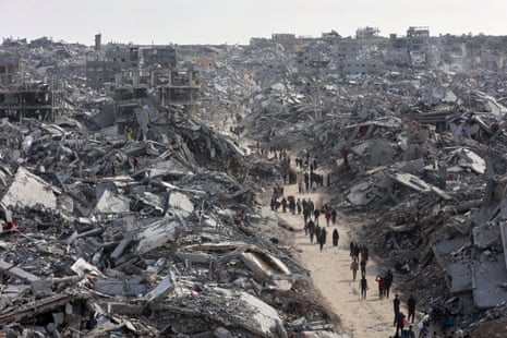 People on a path surrounded by the wreckage of buildings