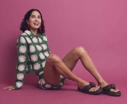 Model in green and white jacket and shorts combo with brown chunky flip-flops on