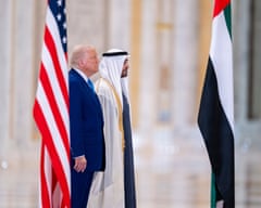 Two men stand beside flags