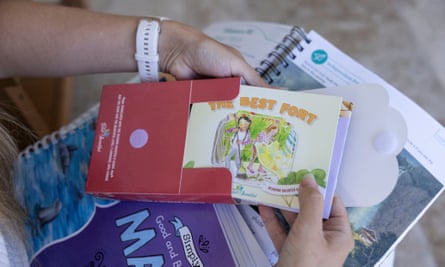 a woman holds several books that are learning materials for home schooling
