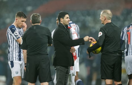 Mikel Arteta, manager of Arsenal, bumps fists with referee Martin Atkinson.