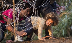 Refugees clamber through barbed wire on their way from Serbia to Hungary.