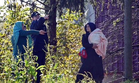 A Croatian police officer directs two women across the Sulta river as migrants and refugees travel across the Croatian-Slovenian border on October near Kljuc Brdovecki.