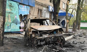 Debris from a destroyed car litter the street at the scene of an explosion near a grocery store in Kharkiv.