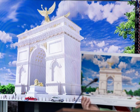 Hands hold laptop showing arch while larger image displayed