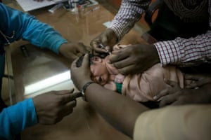 Dr Rakh helps give a free vaccination to a baby girl