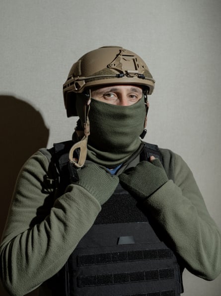 A man wearing military gear stands for a portrait