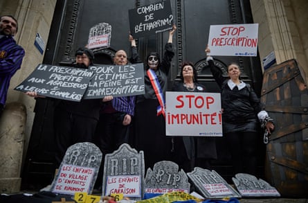 Protesters standing behind fake tombstones hold placards
