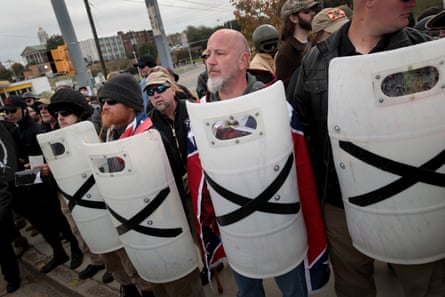 group of white men stand in a row holding white shields with black Xs on them