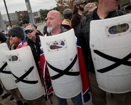 White men hold white shields with black tape crosses on them
