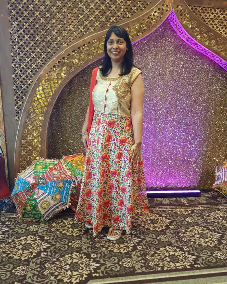 A woman in a long gold and red dress smiles at the camera.