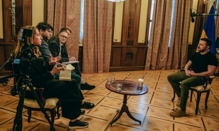 Katharine Viner, Shaun Walker, Nick Hopkins and Luke Harding sit in chairs opposite Volodymyr Zelenskiy in a large room with camera equipment around them