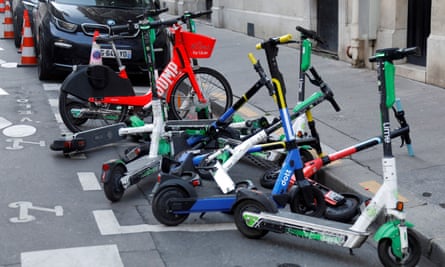 Des scooters électriques sans socle des services de partage Lime et Dott sont garés pour la location dans une rue de Paris.