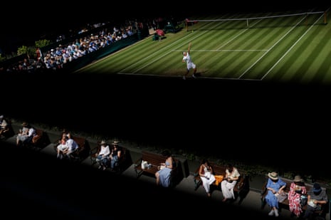 Spectators sitting on benches having lunch watch Lorenzo Sonego serve
