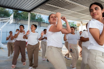 Women take part in a Zumba session in an open area covered by a metal roof
