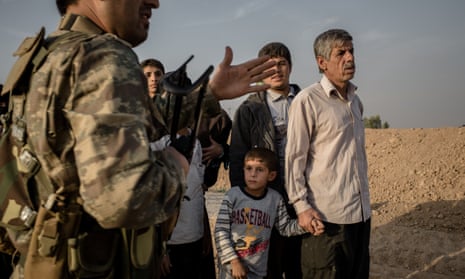A Peshmerga fighter directs displaced citizens at a camp near Khnash, Iraq.