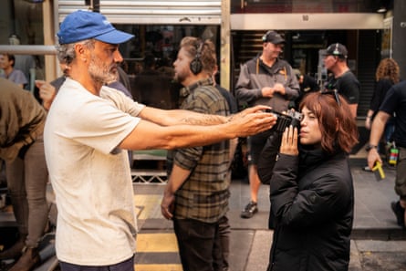 Taika Waititi adjusts a camera held up to Jenna Ortega’s eye on a film set
