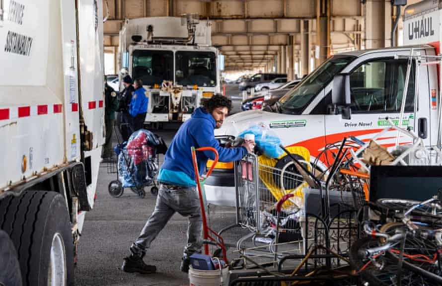 A homeless man tried to salvage his belongings after the area where he had been living was cleared by police officers and sanitation workers.