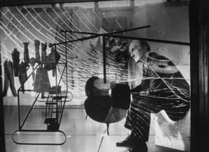 Marcel Duchamp que se está viendo a través del cristal de su obra principal El Gran Vidrio.