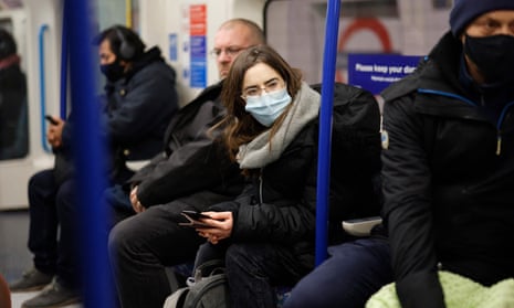 Passengers on the London Underground, some masked, some not. Authorities said facial coverings will be compulsory in shops and on public transport from Tuesday as the UK seeks to avoid further Omicron variant cases.
