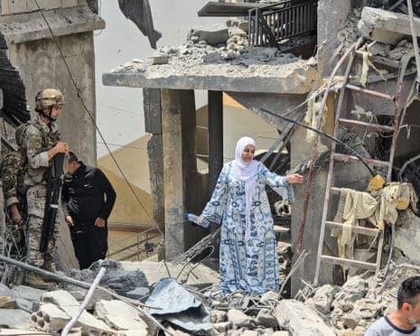 A woman makes her way through the rubble as a Lebanese soldier looks on.