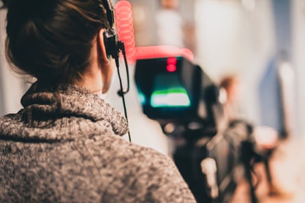 Female cameraman shooting a scene with camera in a film studio.