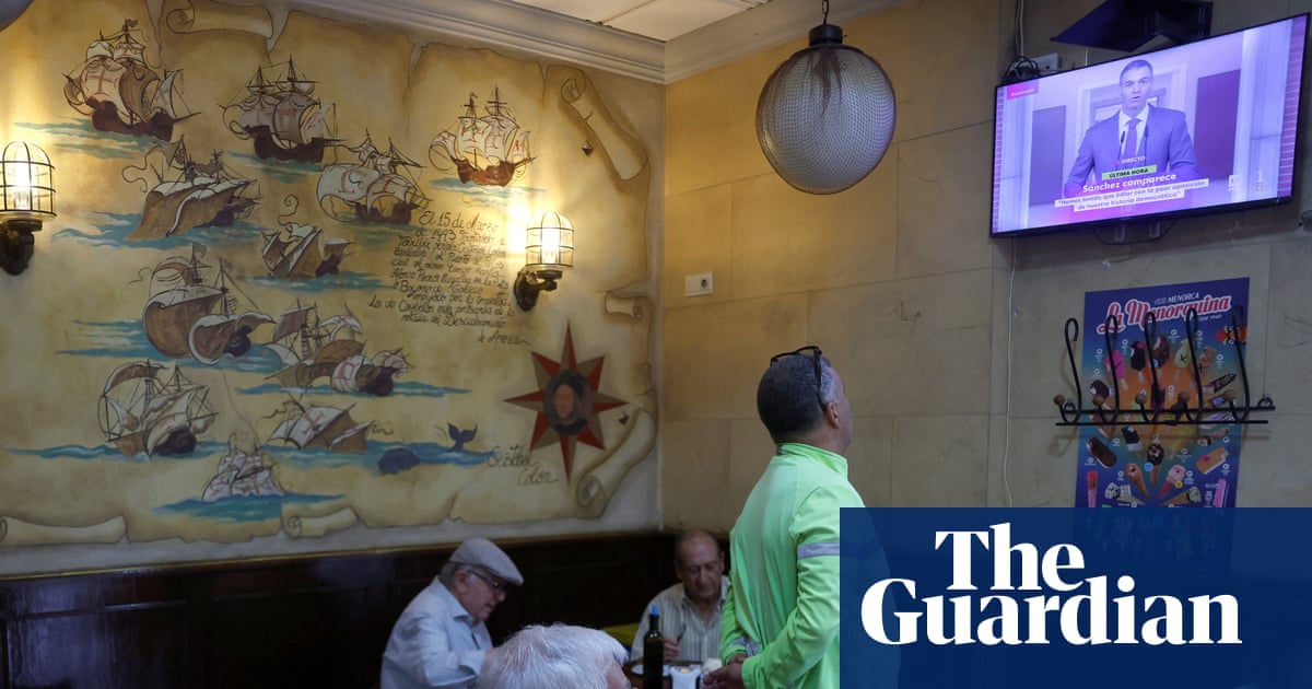 People in a cafe watch a televised address