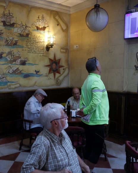 Cafe patrons watch Spain's PM Pedro Sanchez speaking on a wall-mounted television
