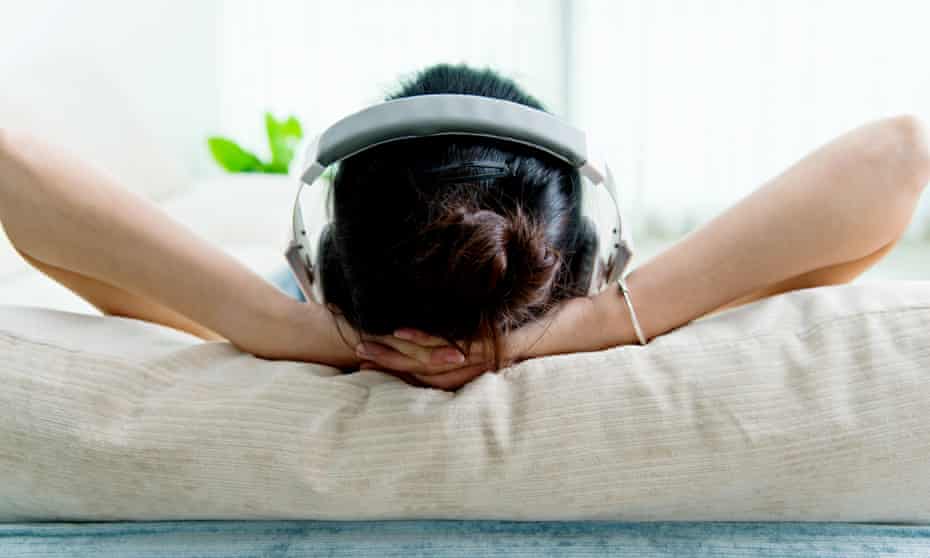 Young woman relaxing on sofa with headphones. 