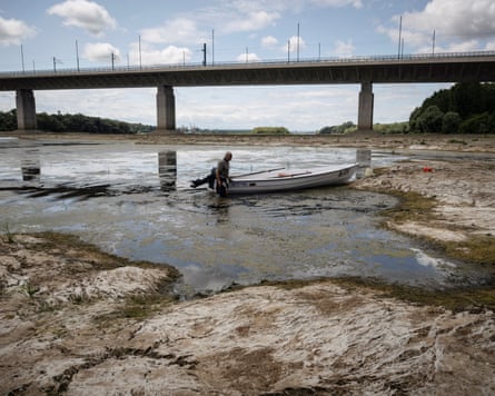 A fisher tries to move his boat, blocked by algae on the bottom of the Danube river, in front of the Calafat-Vidin bridge.