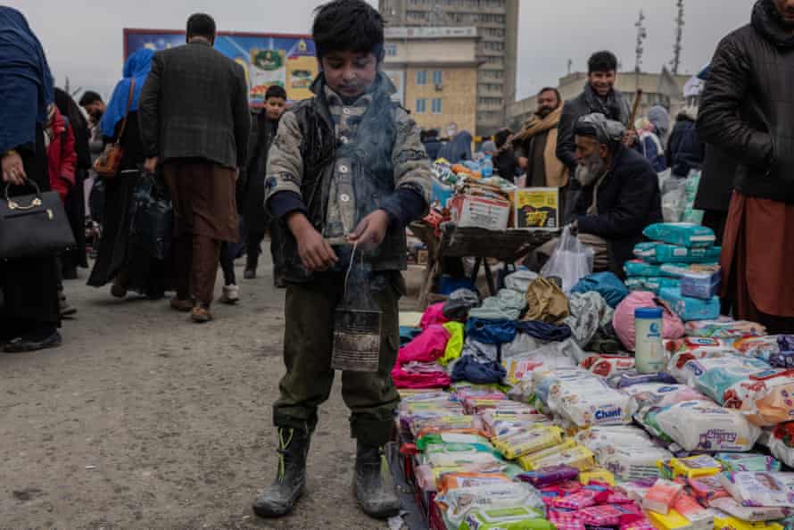 Samim, 6, holds a tin full of Esfand, a seed traditionally burned.  Many Afghans believe its smoke can fight evil.  He works in Kabul's Mandawi Market;  one of the city's busiest.